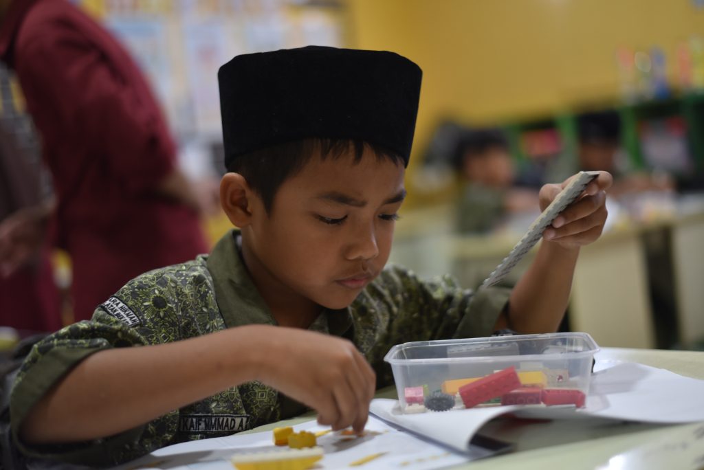 Seorang siswa merakit dan menguji model bermotor dalam kegiatan ekstrakurikuler robotik.